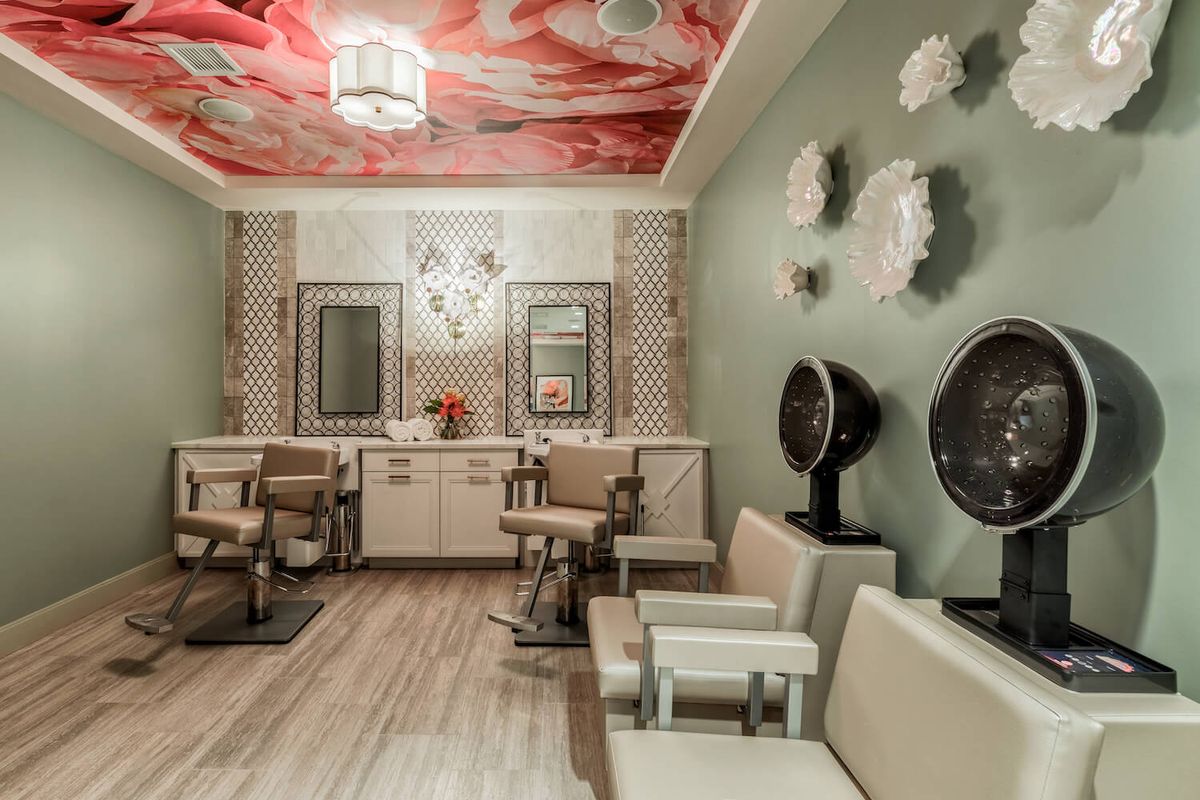 A beautifully designed salon interior featuring stylish chairs, mirrors, wall decor, and ceiling art.