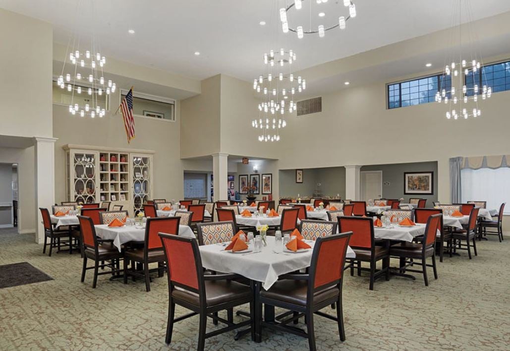 A spacious dining room with elegantly decorated tables and chandeliers.