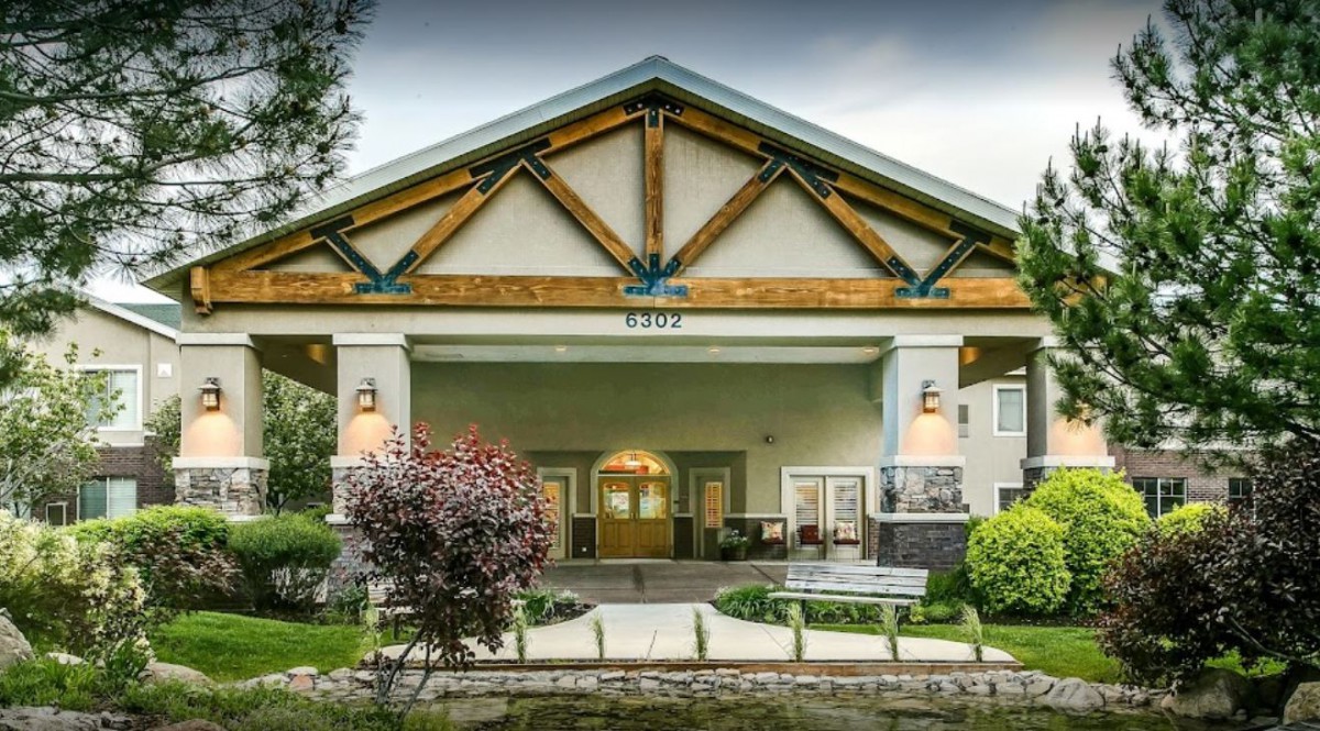 The front entrance of a building featuring prominent wood beams and well-maintained landscaping.