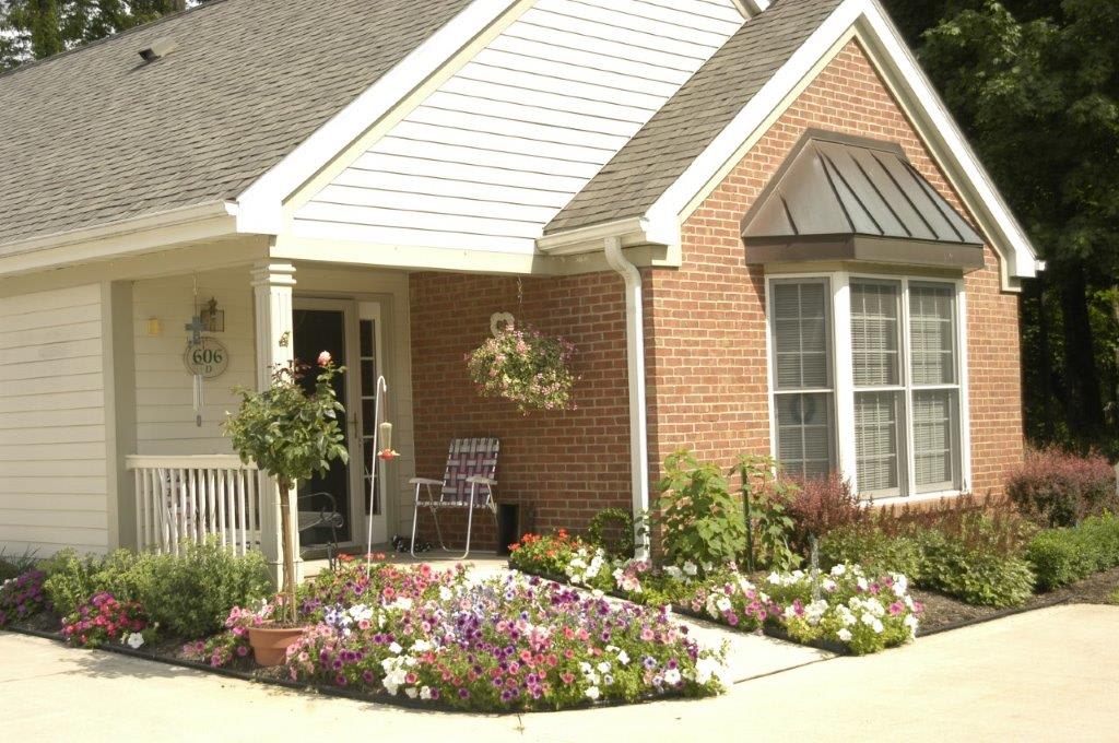A charming brick house with a well-maintained garden full of colorful flowers.