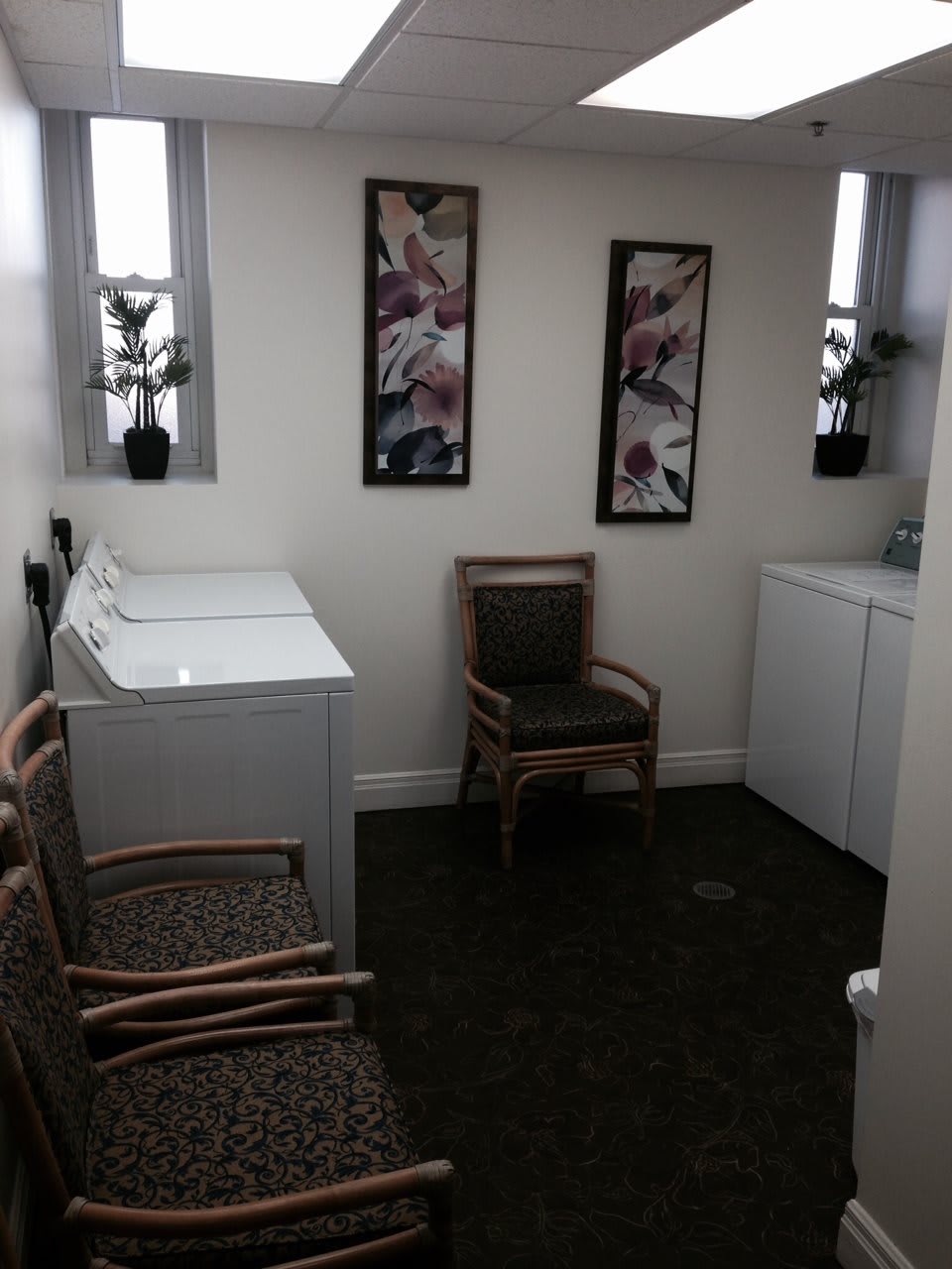 A cozy laundry room featuring washing machines, seating, and decorative wall art.