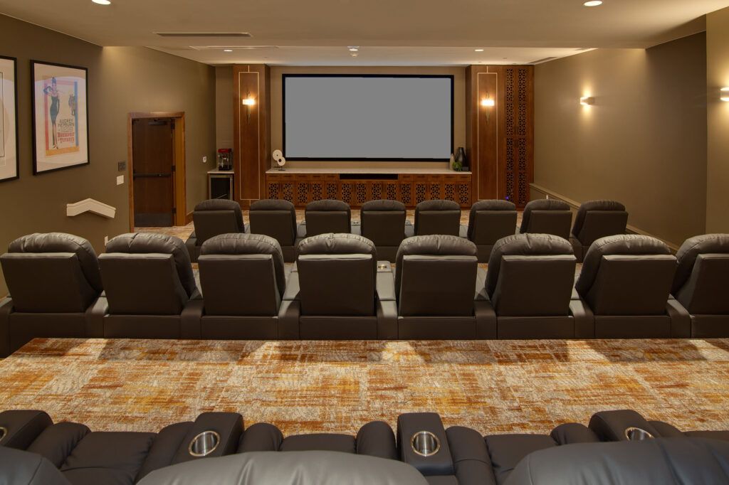 A home theater with multiple rows of comfortable seating facing a large screen.