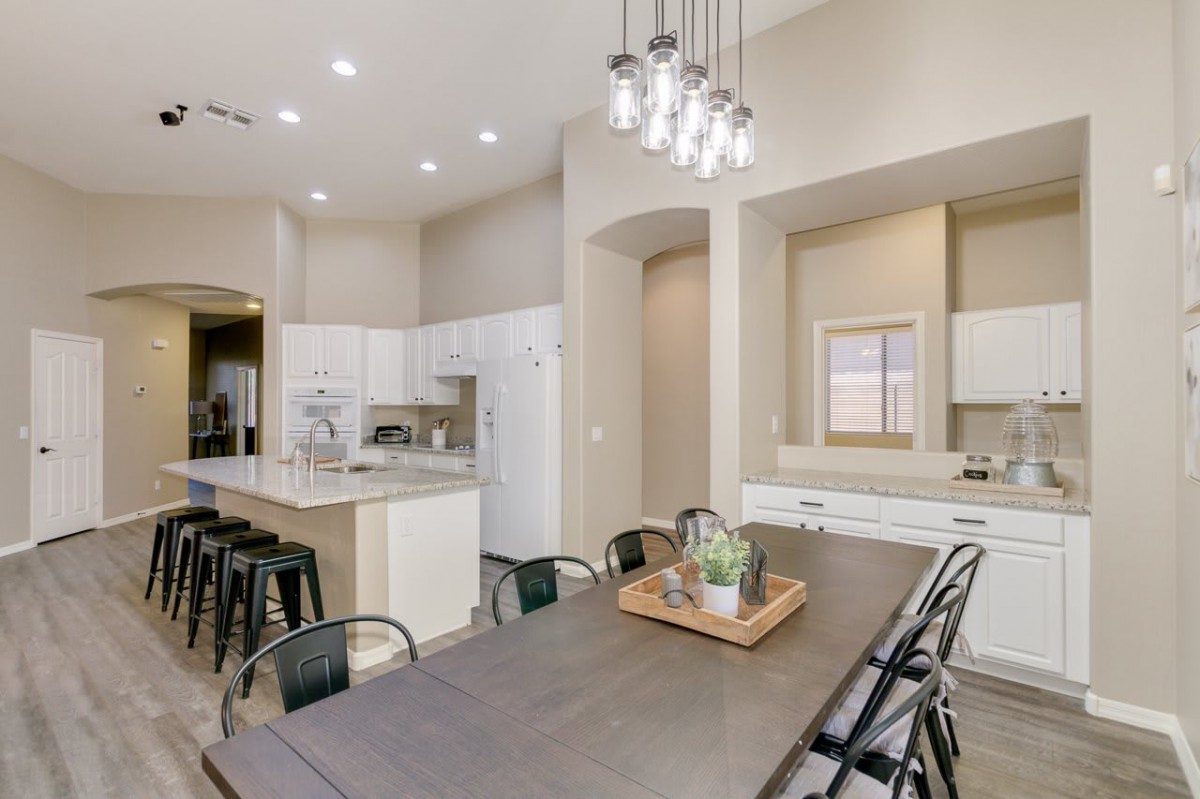A modern kitchen and dining area with an open concept design, featuring sleek lighting fixtures and a spacious layout.