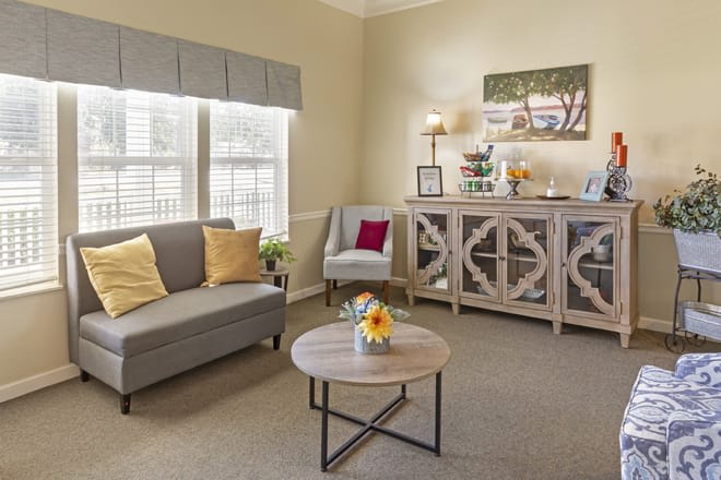 A cozy living room with a sofa, armchair, and decorative cabinet.