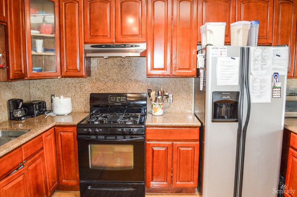 A modern kitchen with wooden cabinets, featuring a stove and refrigerator.