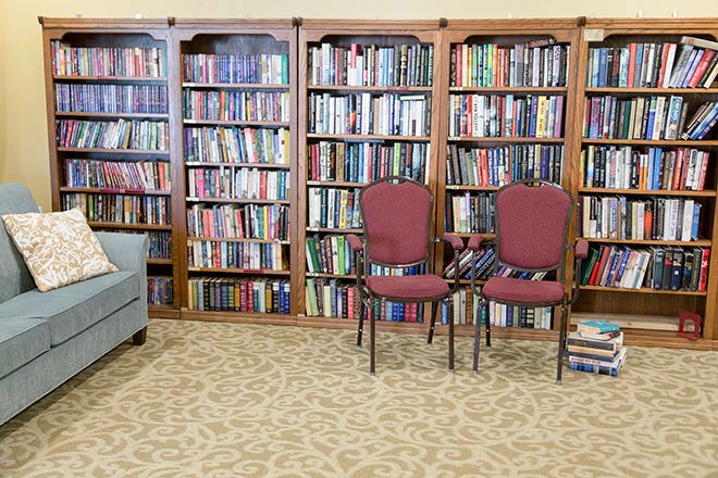 A cozy library corner with bookshelves full of books and a couple of chairs.