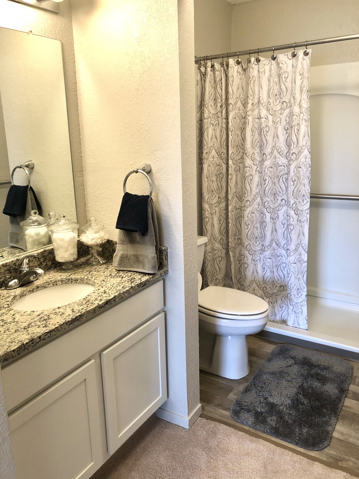 A well-organized bathroom with a sink, mirror, toilet, and shower.