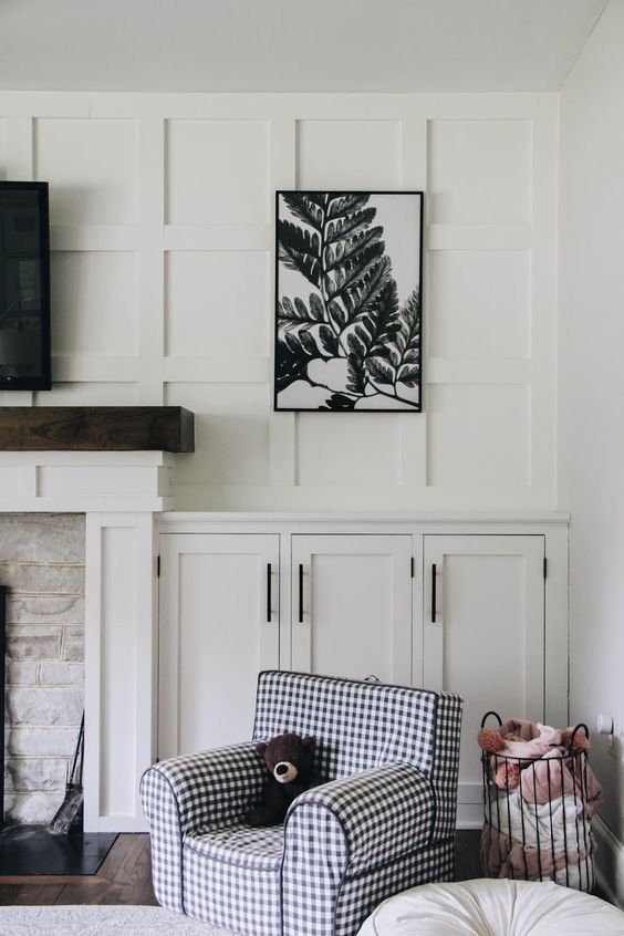 A cozy living room corner with a framed artwork above the fireplace and a patterned armchair.