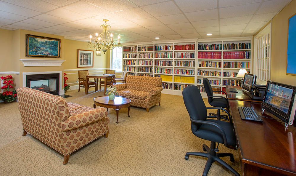 A cozy library room with bookshelves, seating, and a chandelier.