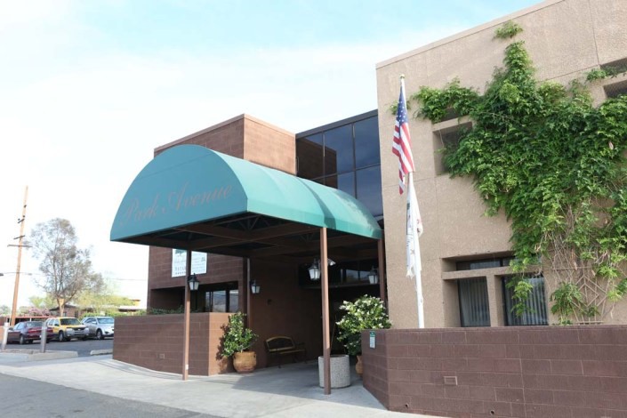 A building entrance with a green canopy and flagpole.