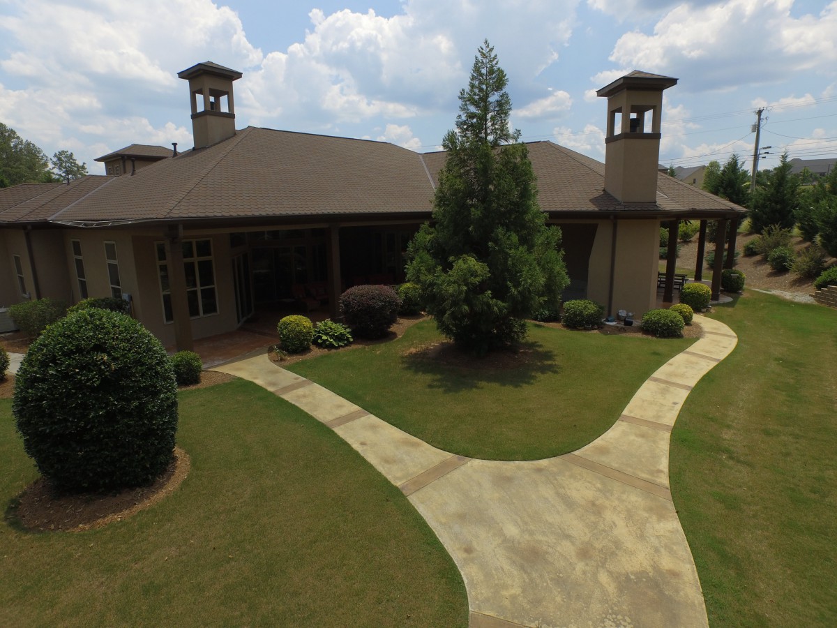 A spacious residential house with a well-maintained lawn and neatly paved pathways.