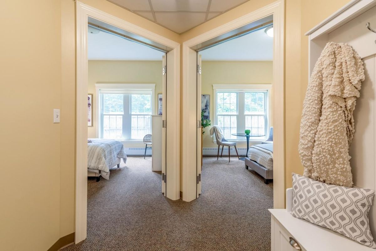 A view of two adjacent bedrooms with large windows and cozy interiors.