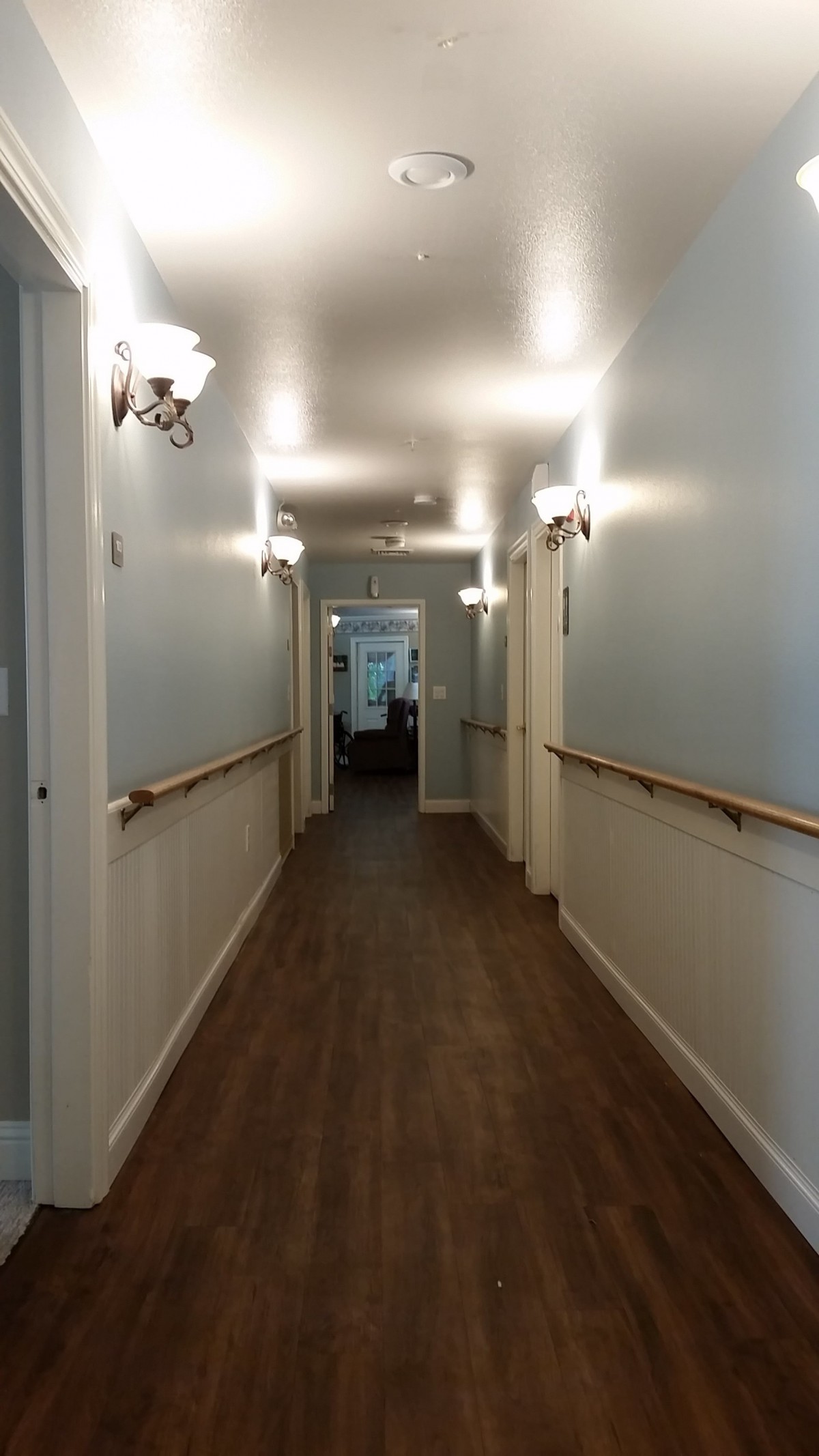 A well-lit indoor hallway with wooden flooring and railings on both sides.