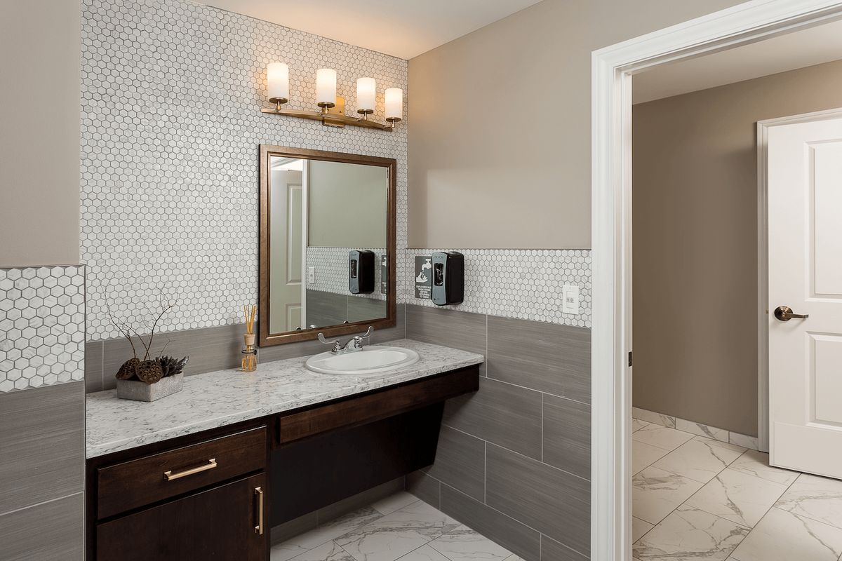 A modern bathroom featuring a stylish vanity with a marble countertop, elegant lighting, and contemporary tile design.