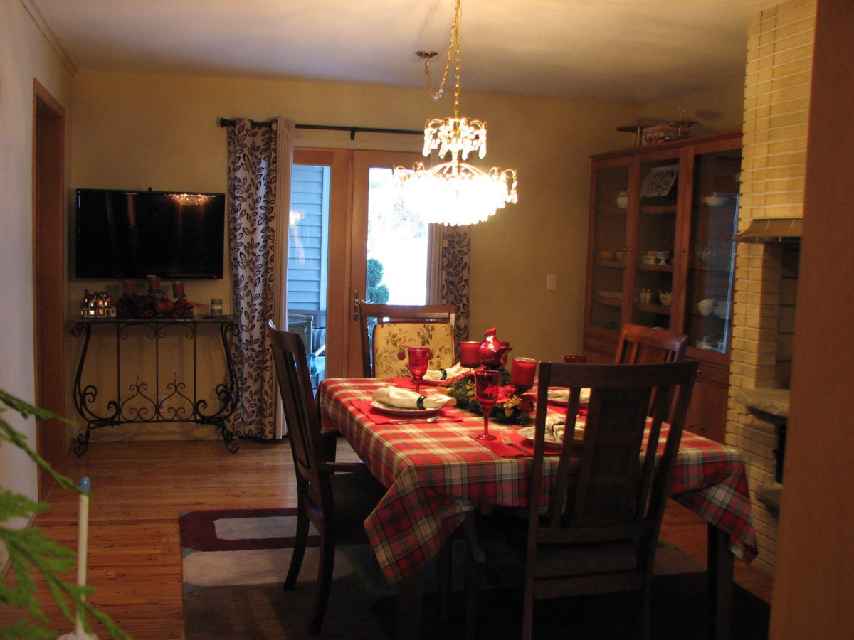 A cozy dining room with a decorated table and a chandelier.