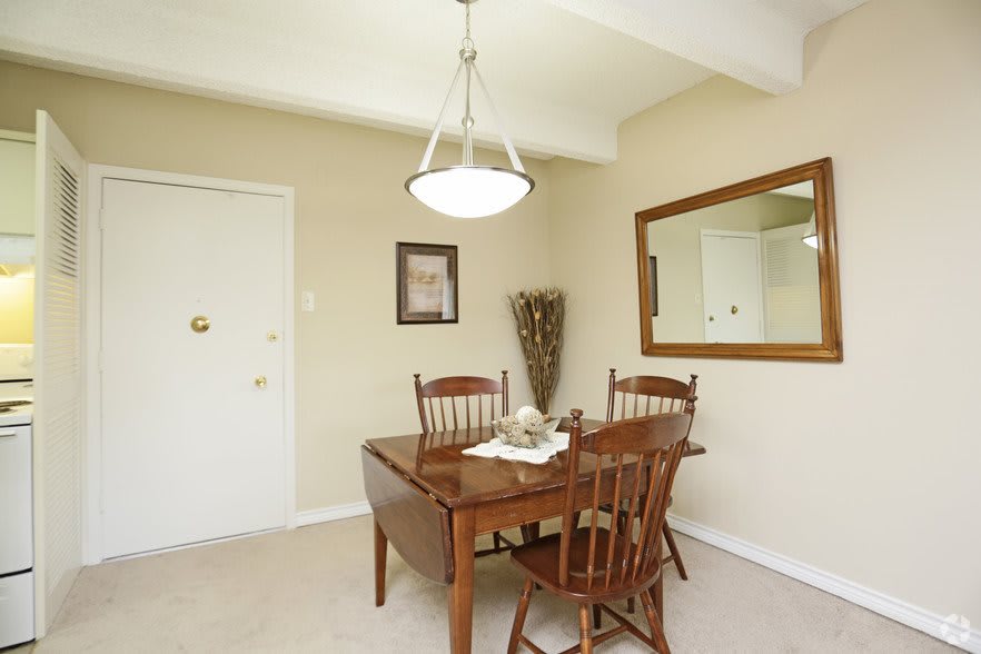 A cozy dining room with a wooden table and chairs, decorated with a wall mirror and artwork.