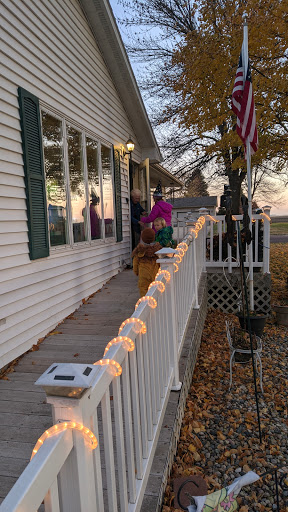 A cozy house adorned with festive lights, showcasing the beauty of autumn during sunset.