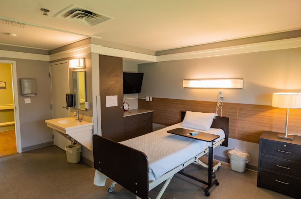 A clean and organized hospital room with a single bed and medical equipment.