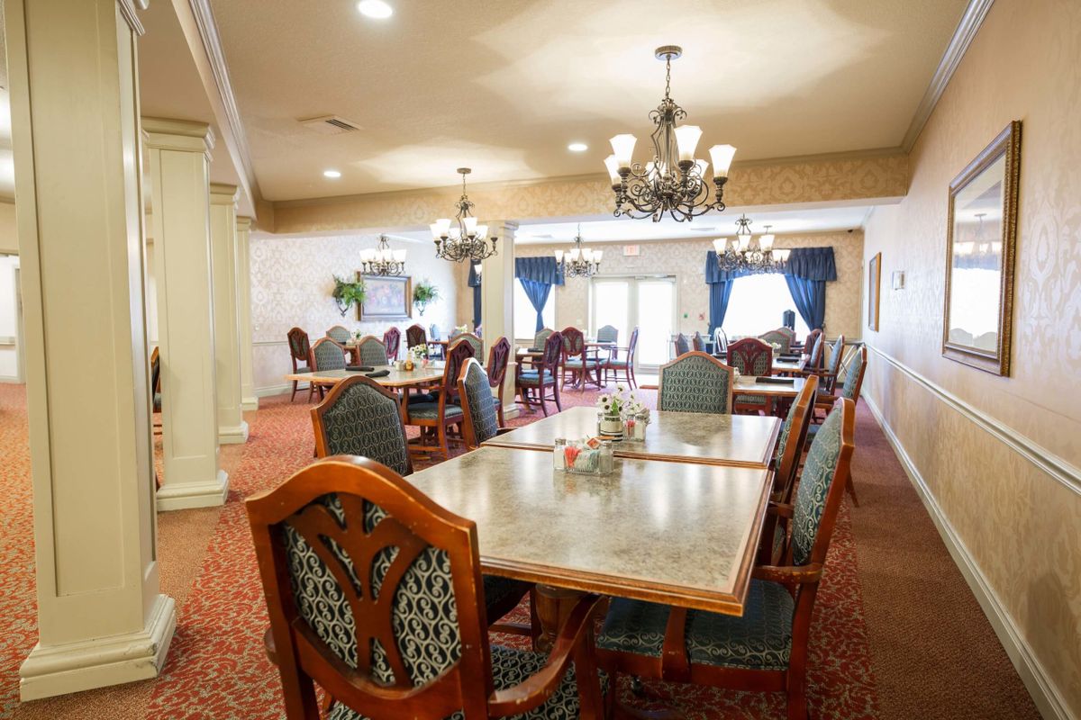 An elegant dining room with chandeliers and neatly arranged tables and chairs.