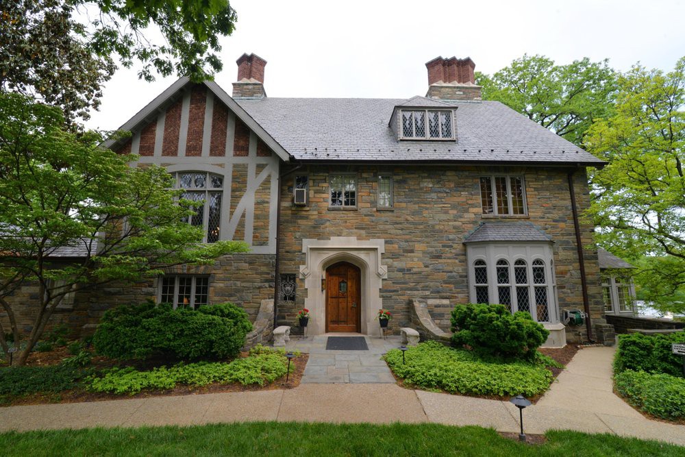 A charming Tudor-style stone house with beautiful landscaping.