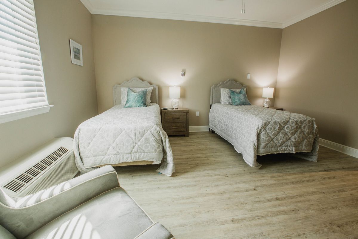 A modern bedroom with twin beds and neutral decor.