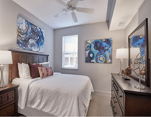 A cozy bedroom featuring colorful artwork, a neatly made bed with pillows, and elegant decor.