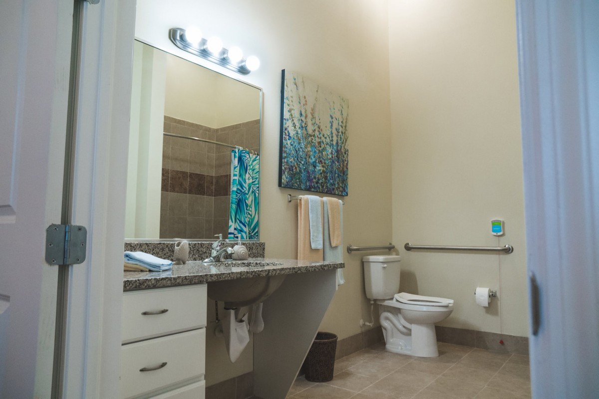 A modern bathroom with a sink, mirror, and artwork on the wall.