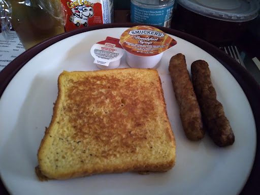 A delicious breakfast plate featuring golden french toast, sausage links, and a side of maple syrup.