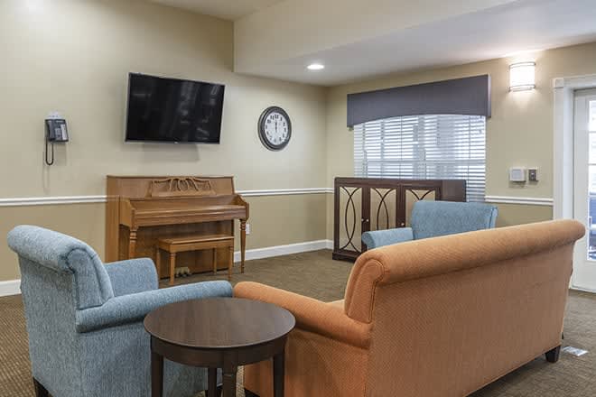 A cozy living room featuring a piano, television, and comfortable seating.