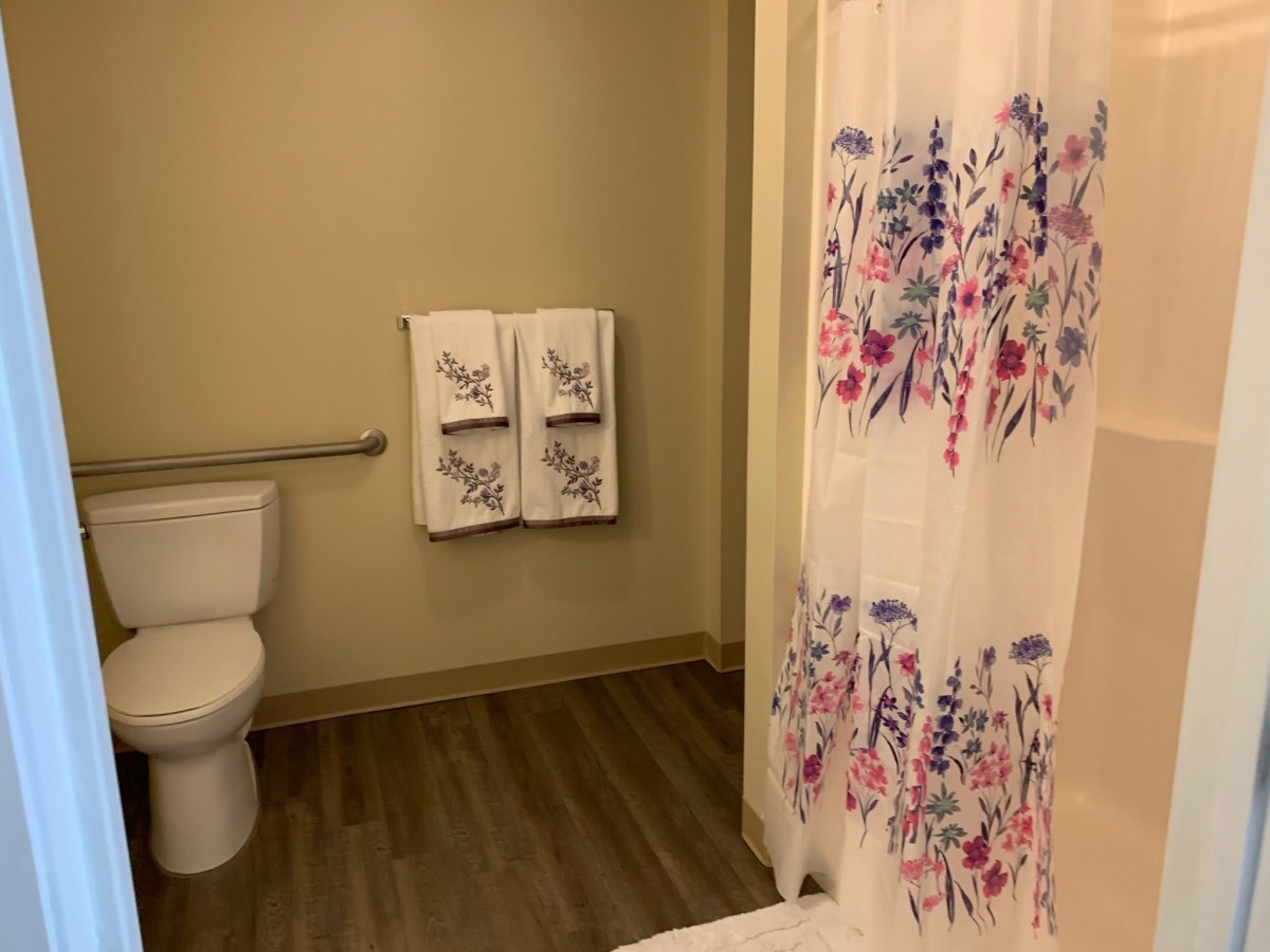 A bathroom with floral shower curtain and neatly hung towels.