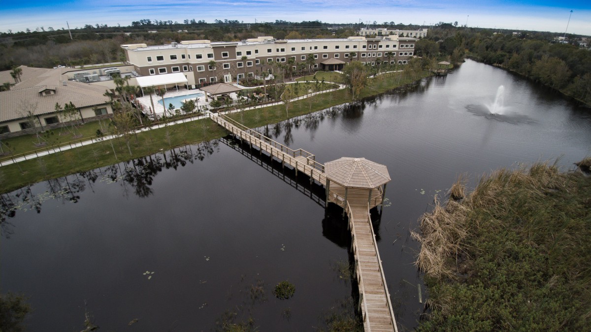 Aerial view of a hotel with a boardwalk extending over a lake, providing a serene waterfront experience.