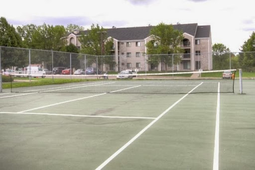A view of empty tennis courts surrounded by residential buildings and greenery.