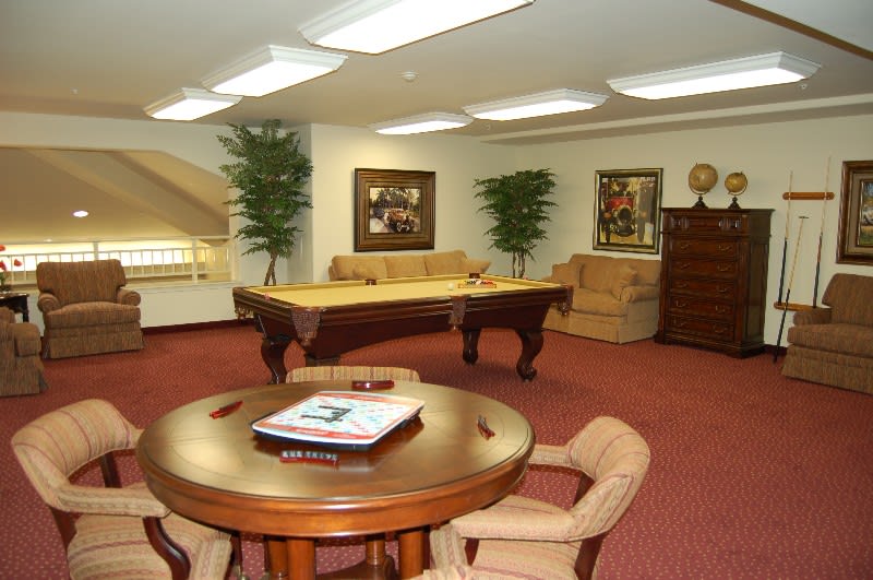 A cozy game room featuring a billiards table, seating area, and warm interior decor.