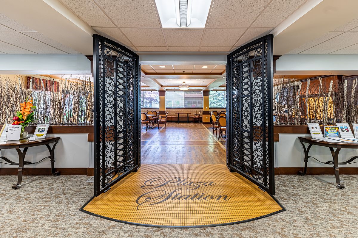 An inviting restaurant entrance with decorative iron gates leading to a spacious dining area with wooden floors.