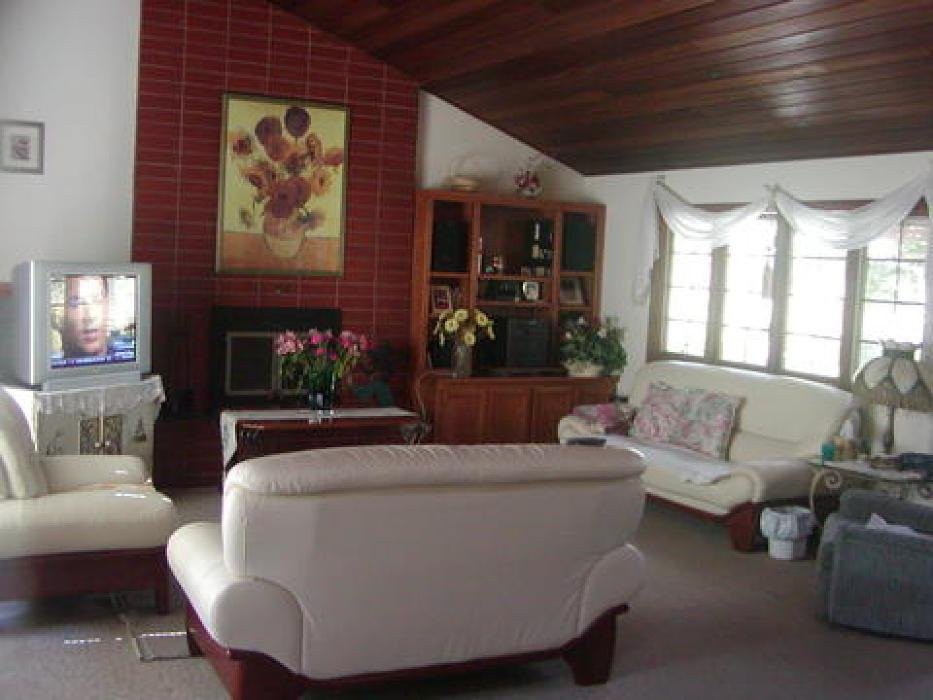 A cozy living room with white sofas, a brick fireplace, and various decorations.