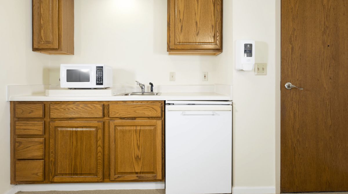 A kitchen area with wooden cabinets, a microwave, sink, and dishwasher.