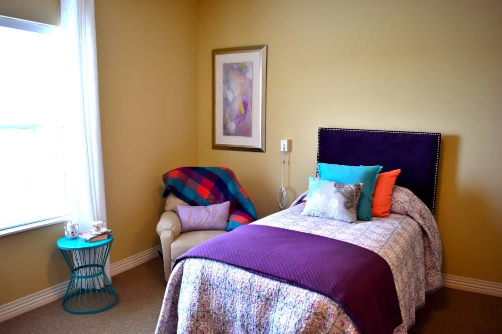 A cozy bedroom with a colorful bed and a comfortable armchair.