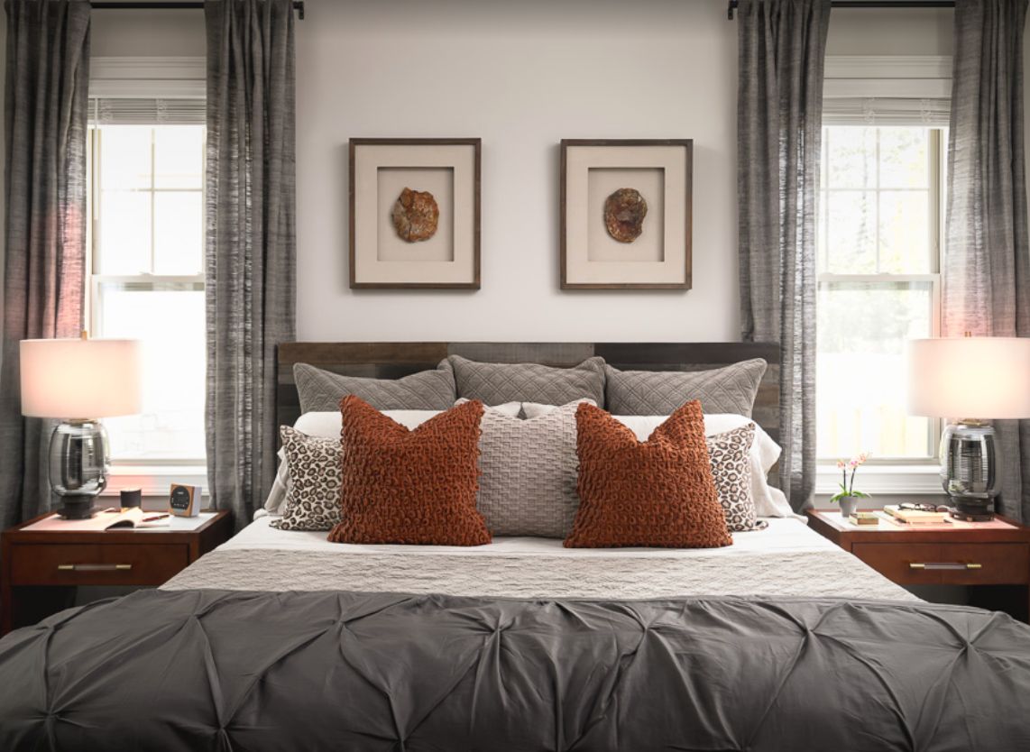 A cozy and stylish bedroom with a neatly arranged bed, featuring decorative pillows and framed artwork above the headboard.