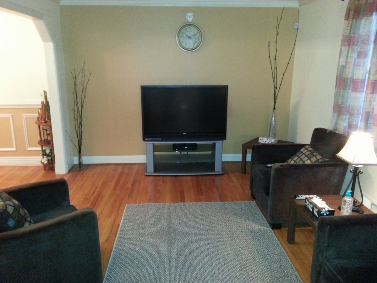 A minimalist living room with a television, sofas, and a clock on the wall.