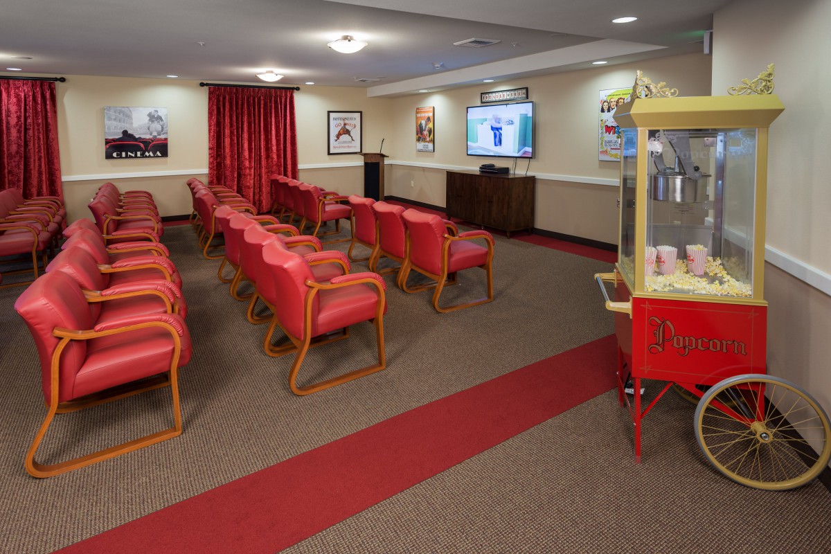 A small movie theater with red chairs and a popcorn machine.