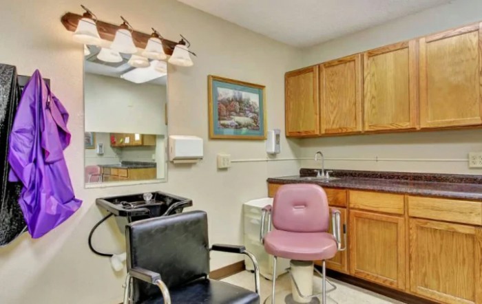 A small salon setup with chairs, mirror, and cabinets.