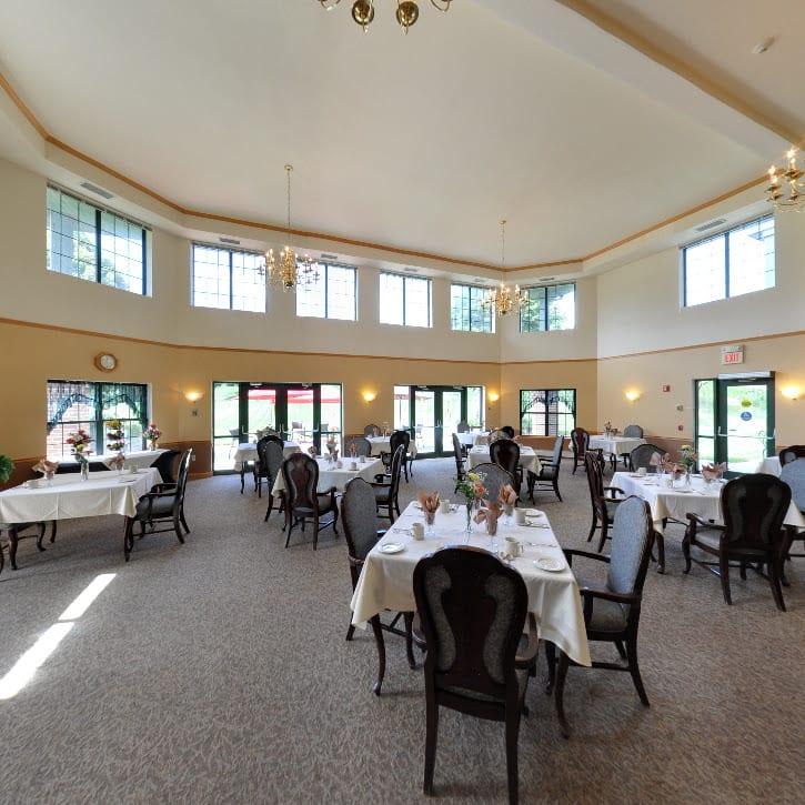 A spacious dining area with elegantly set tables and large windows letting in natural light.