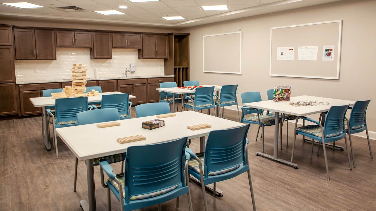 A modern classroom setting with tables and blue chairs arranged for a meeting or educational session.
