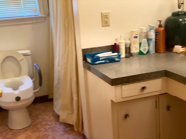 A bathroom with a toilet, sink, and various toiletries on the counter.