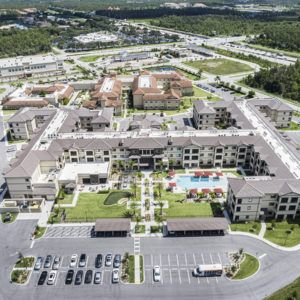 Aerial view of a residential apartment complex featuring a central swimming pool and surrounding parking lots.