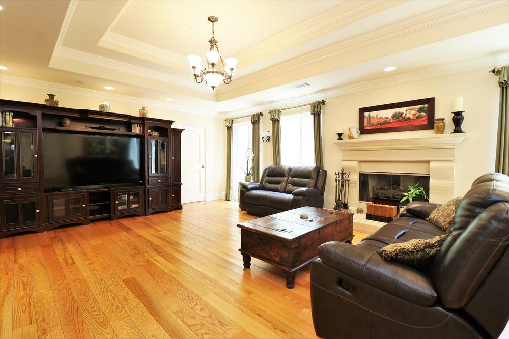 A cozy living room with hardwood floors, leather sofas, a coffee table, and a fireplace.
