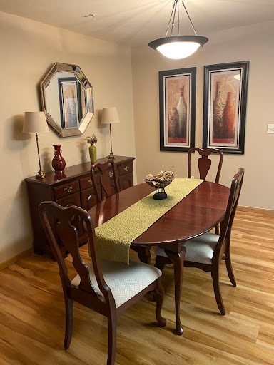 A cozy dining room featuring an elegant wooden dining table and chairs, complemented by stylish wall art and lamps.