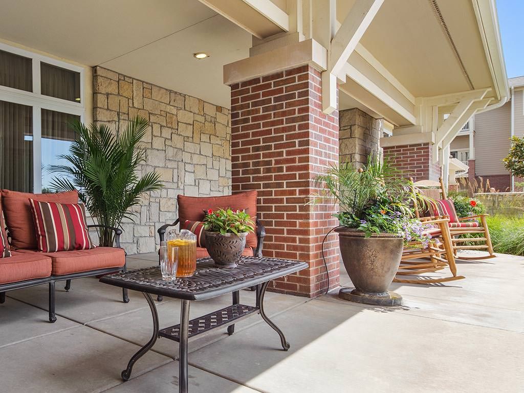 A cozy porch with comfortable seating and potted plants, perfect for relaxation.