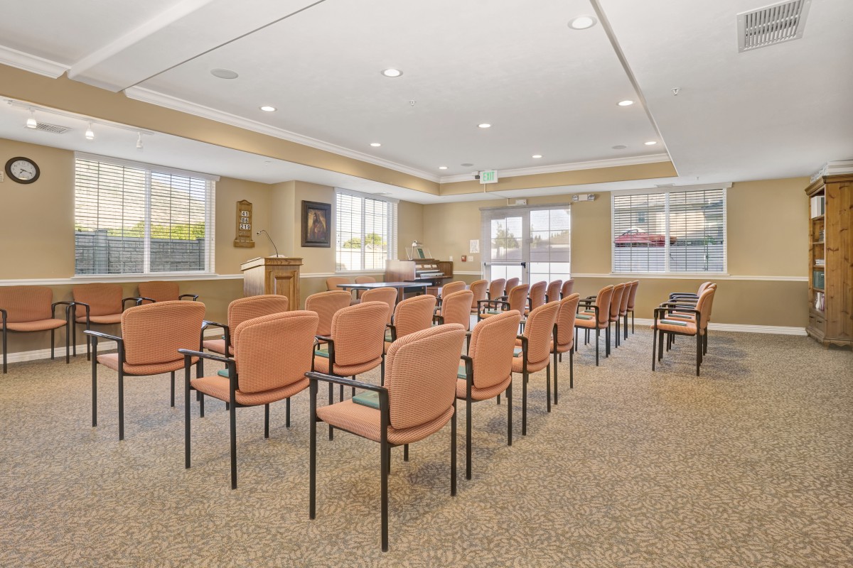 An empty meeting room with rows of chairs and a piano near the window.