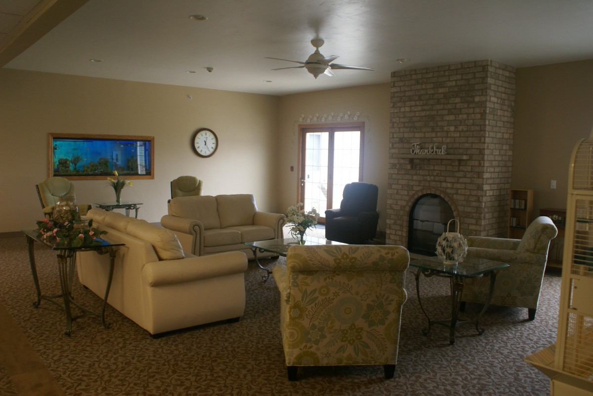 A cozy living room with sofas, a fireplace, and a TV mounted on the wall.